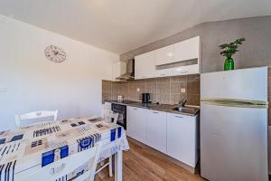 une cuisine avec des armoires blanches et un réfrigérateur dans l'établissement Apartment Ivana near the beach, à Otočić Ošjak 31 autres photos