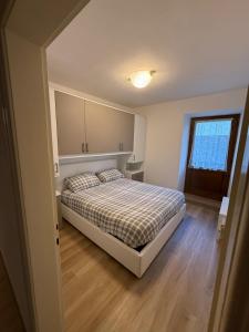 a bedroom with a bed with a checkered blanket at Appartamento Moena in Moena
