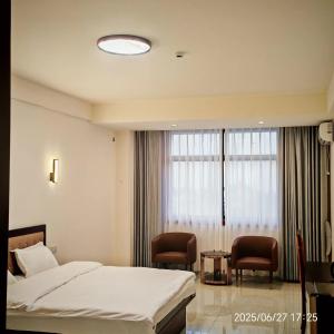 a bedroom with a bed and two chairs and a window at Jiang Su Hotel in Brazzaville +4 photos