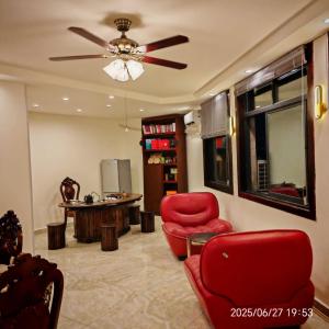 a living room with red chairs and a ceiling fan at Jiang Su Hotel in Brazzaville