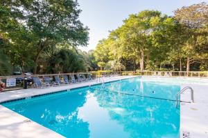 a swimming pool with chairs and trees in the background at IC106: 106 Inlet Cove in Kiawah Island