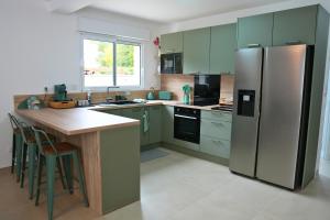 una cucina con armadi verdi e frigorifero in acciaio inossidabile di Maison détente & confort près de Disney - 25 min a La Haute-Maison Altre 23 foto