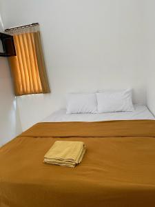 a bed with a towel laying on top of it at NOWORRIES Banyuwangi in Banyuwangi