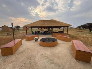 a pavilion with a table and benches in a field at Shumba Camping Site in Mahikeng