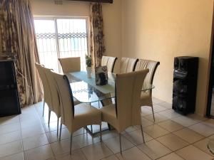 a dining room with a glass table and chairs at Horizon small holding in Polokwane