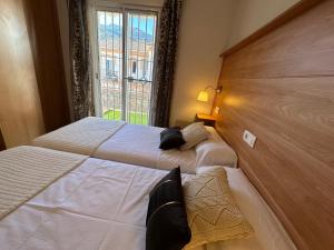 twee bedden in een hotelkamer met een raam bij Nevada Suites Guejar in Güéjar-Sierra