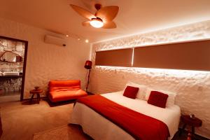 a bedroom with a bed and an orange chair at Vila Kairós - 1 Cabana privativa com banheira e 2 suítes independentes - Vista Incrível Cozinha Gourmet Fogueira in Alto Paraíso de Goiás