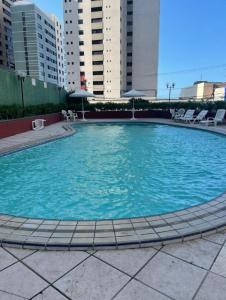 a large pool of blue water with chairs and buildings at Quarto mobiliado na orla de Iracema in Fortaleza