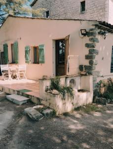 una casa antigua con 2 sillas y un porche en Gîte Des Louveteaux, en Berrias Et Casteljau