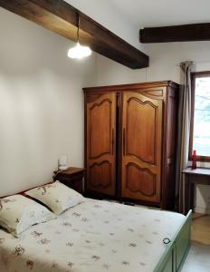 Un dormitorio con una cama y un armario de madera. en Gîte Des Louveteaux, en Berrias Et Casteljau