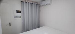 - une chambre blanche avec un lit et un rideau dans l'établissement Luxury Oaks Apartment, à Flic-en-Flac 29 autres photos