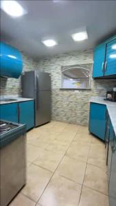 Una cocina con gabinetes azules y un refrigerador de acero inoxidable. en KHadma vip, en Banī Ghālib