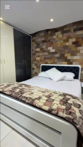 Un dormitorio con una cama y una pared de ladrillo. en KHadma vip, en Banī Ghālib