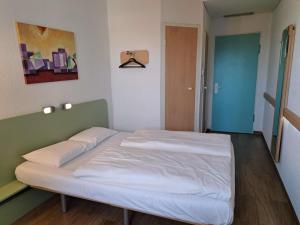 Un dormitorio con una cama blanca en una habitación. en ibis budget Berlin Ost, en Berlín 23 fotos más