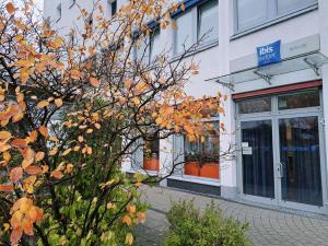 Un edificio con un cartel azul al lado de un árbol. en ibis budget Berlin Ost, en Berlín