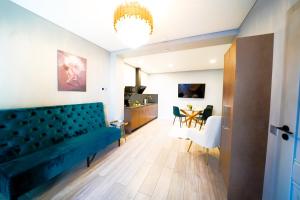 a living room with a blue couch and a dining room at Svaja ApartHotel in Šiauliai