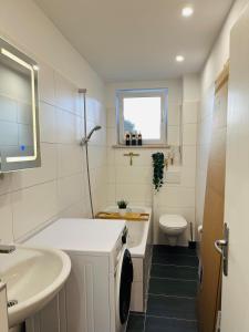 a white bathroom with a sink and a toilet at YAYstay - Forest I 65m2 I Balcony I TV I Bahnhof in Mühldorf