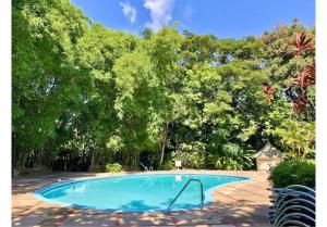 an empty swimming pool with trees in the background at Tropical Escape Villa in Ocho Rios