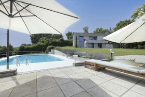 une piscine avec un parasol et une terrasse avec un canapé et un parasol dans l'établissement Villa Itaca, à Casorzo