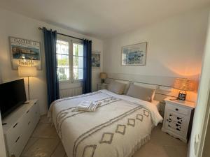 una camera da letto bianca con un letto e una televisione di Arlore a Grimaud