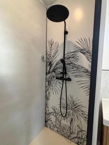 a shower with a black and white plant mural on the wall at DACSE-VILLAGE - Gite 03 in Dax