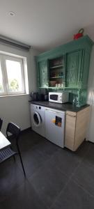 eine Küche mit Waschmaschine und Mikrowelle in der Unterkunft La Valériane in Moyeuvre-Grande