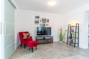 a living room with a red chair and a tv at Bodensee Gateway - Stockach in Stockach