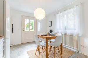 a dining room with a wooden table and white chairs at Bodensee Gateway - Stockach in Stockach