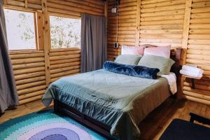 a bedroom with a bed in a log cabin at Mágica Cabaña con jacuzzi en Santa Elena in Santa Elena