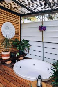 a bath tub sitting on a wooden deck with plants at Mágica Cabaña con jacuzzi en Santa Elena in Santa Elena