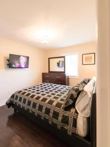 Un dormitorio con una cama y un televisor en la pared. en Walk To The Beach, en Fort Erie