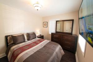 Un dormitorio con una cama con una cómoda y un espejo. en Walk To The Beach, en Fort Erie