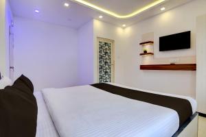a bedroom with a white bed and a tv on the wall at Hotel O Acroview in Ballygunge