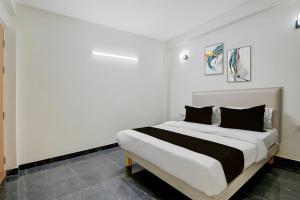a white bedroom with a large bed with black pillows at Hotel O Kalka in Indraprast
