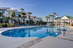 a swimming pool with chairs and houses and palm trees at OP58: 58 Ocean Point in Isle of Palms