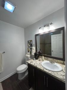 Un baño con lavabo, inodoro y espejo. en Fully Furnished 2 bedroom, en Brownsville