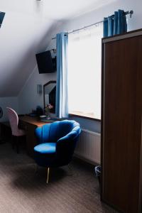 a room with a blue chair and a desk and a window at GAJOVA Restauracja & Nocleg in Pobiedziska