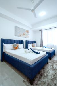 two beds in a room with blue furniture at Bubbles Cozy Homes Two bedroom apartment in Mombasa