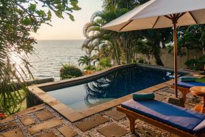 una piscina con sombrilla junto al océano en Aquamarine Seaview Villa, en Amed
