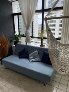 a blue couch in a room with a hammock at Quarto a 10m da praia ao lado de Pubs e Restaurantes in Recife