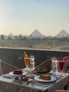 カイロにあるGrand Galleria Pyramids Hotelの食べ物と飲み物の盛り合わせが付いたテーブル