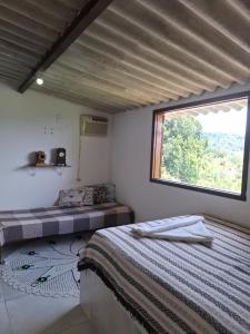 a bedroom with a bed and a large window at Paraty Mirim - Refugio Montanha in Paraty