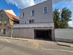 a building with a parking garage next to a street at Gabi Papa Apartman in Pécs