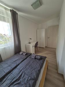 a bedroom with a bed and a desk and a window at Gabi Papa Apartman in Pécs