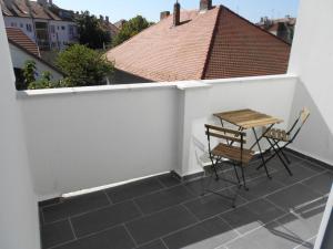 a patio with two chairs and a table on a balcony at Gabi Papa Apartman in Pécs +3 photos