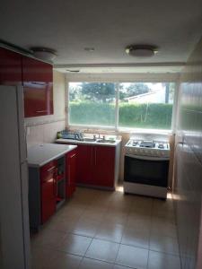 a kitchen with red cabinets and a stove and a window at Casa coco in Texcalpan