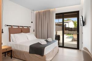 a bedroom with a bed and a sliding glass door at Luxury Suites with private pool and BBQ by Kalles Homes & Suites in Áno Kalésia +80 photos