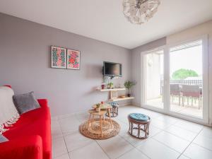 ein Wohnzimmer mit einem roten Sofa und einem Fernseher in der Unterkunft LEscale Détente - Genas Lyon Eurexpo St Exupéry in Genas