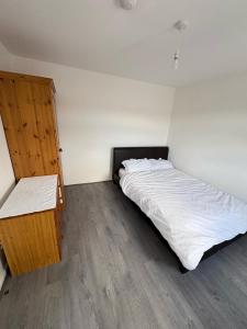 Schlafzimmer mit einem weißen Bett und einem Holzschrank in der Unterkunft Bronze house in Friern Barnet + 1 Foto