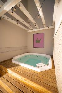 uma banheira de hidromassagem num quarto com pisos de madeira em Bossa Jurerê Hotel em Florianópolis